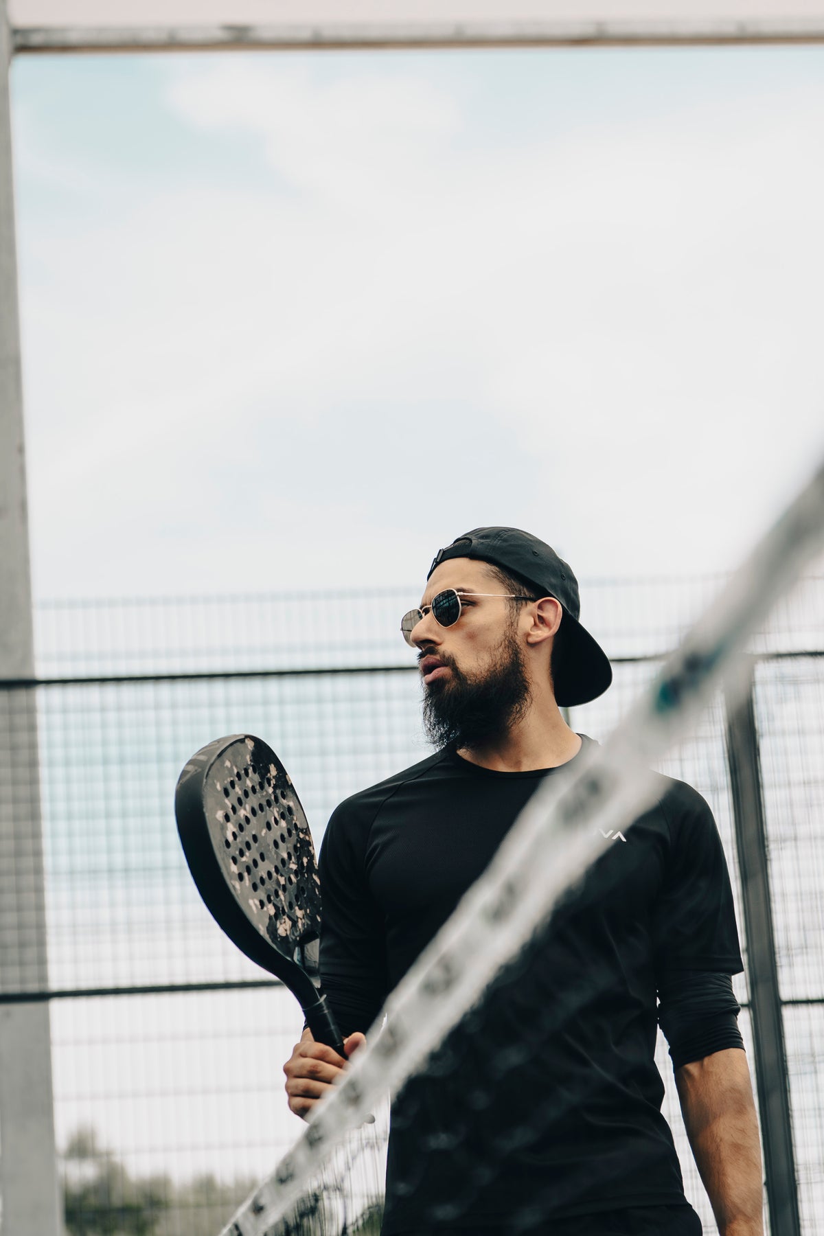 Hand resting on an Aurum racket, showing its gold-leaf and carbon finish