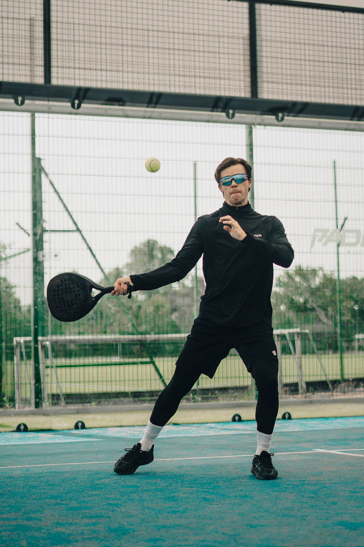 Alex preparing a shot with a KUVA racket, shown in monochrome